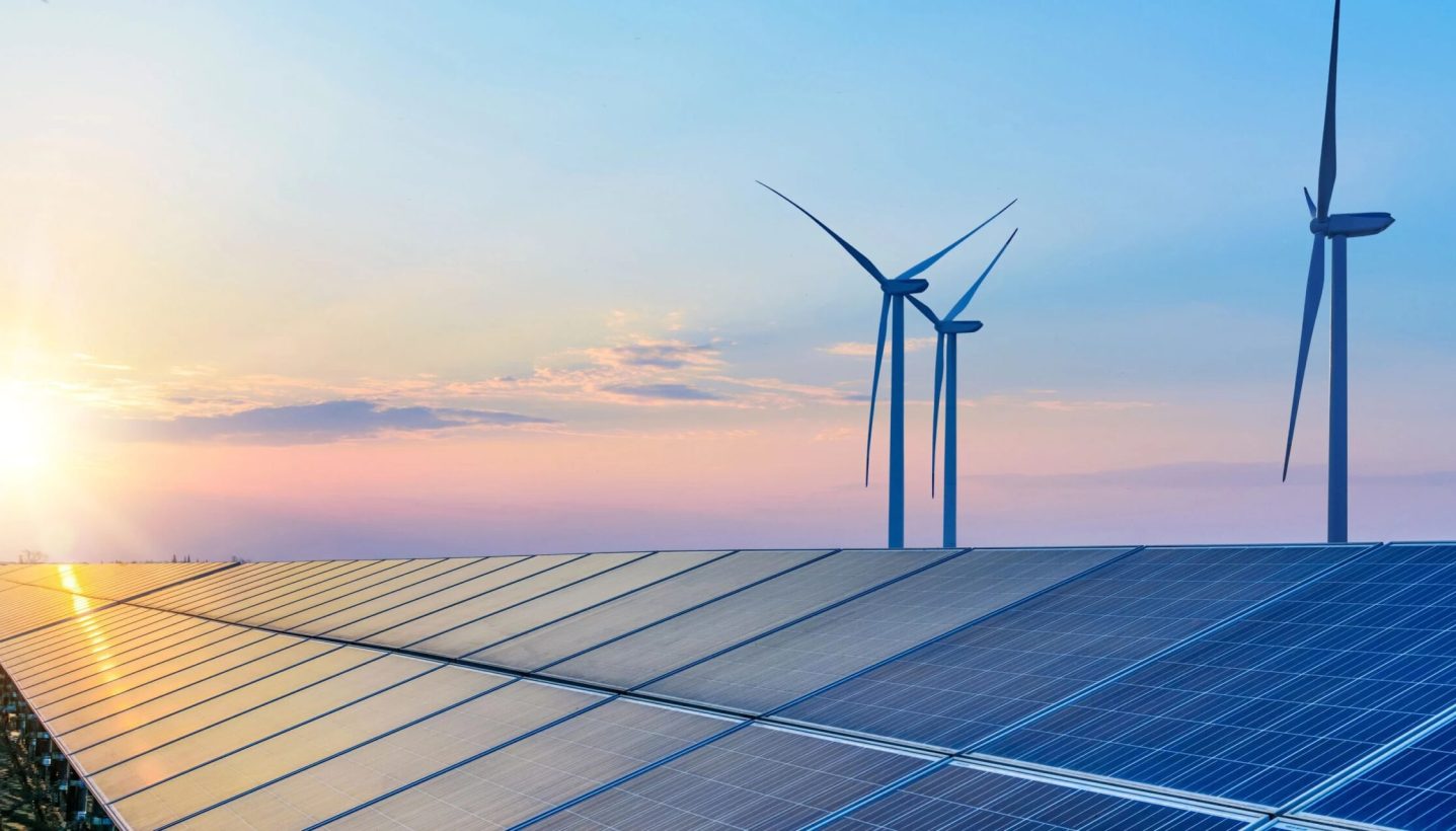 Solar panels and wind turbines at sunset